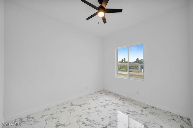 empty room with a ceiling fan, marble finish floor, and baseboards