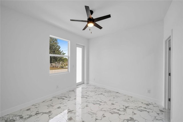 empty room featuring a ceiling fan, marble finish floor, and baseboards