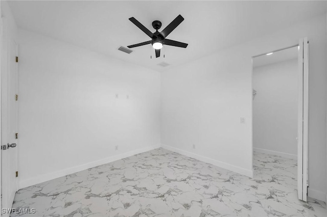 empty room with marble finish floor, a ceiling fan, visible vents, and baseboards