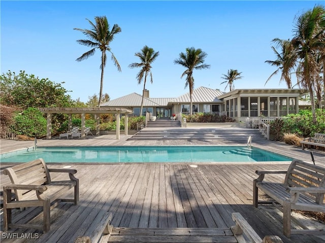 community pool with a sunroom, a patio, a deck, and a pergola