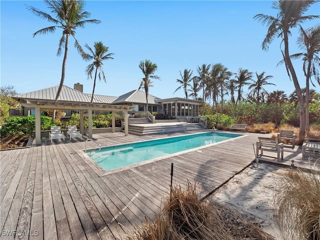 outdoor pool featuring a sunroom, a deck, and a gazebo