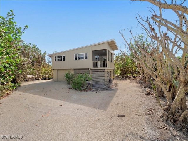 view of side of property with a garage, a sunroom, and driveway