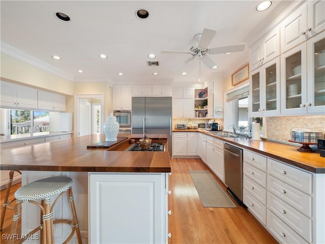 kitchen featuring a sink, appliances with stainless steel finishes, butcher block counters, and white cabinetry