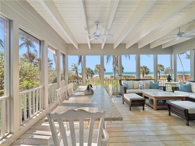 sunroom with ceiling fan and beam ceiling