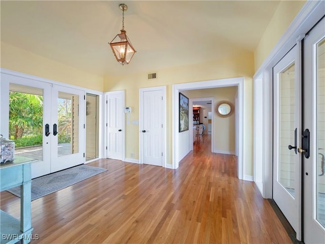 foyer entrance with french doors, light wood-style flooring, visible vents, and baseboards