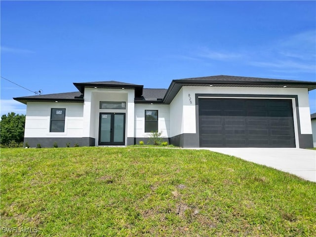 prairie-style home featuring a front lawn, concrete driveway, stucco siding, french doors, and a garage