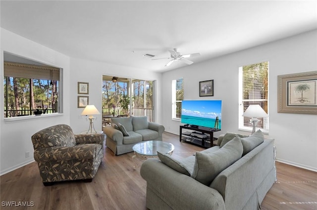 living area featuring visible vents, baseboards, a ceiling fan, and wood finished floors