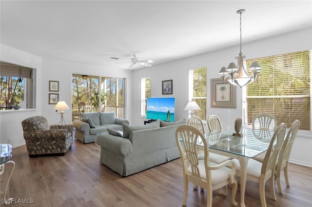 dining area featuring ceiling fan with notable chandelier and wood finished floors