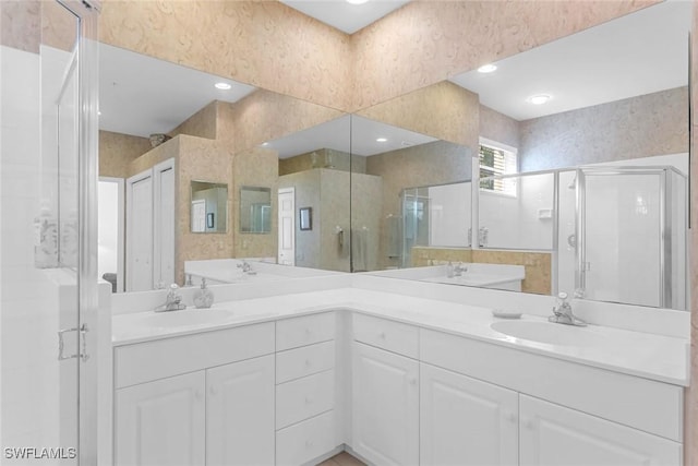 bathroom featuring double vanity, a shower stall, and a sink