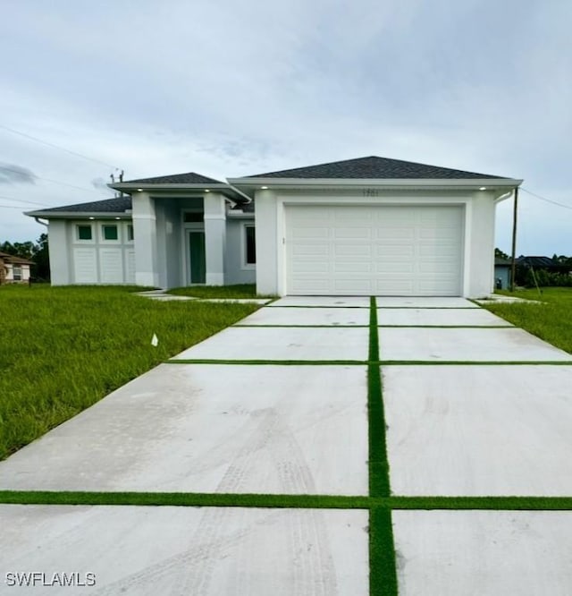 prairie-style house featuring a garage, concrete driveway, a front lawn, and stucco siding