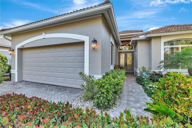 garage with decorative driveway and french doors