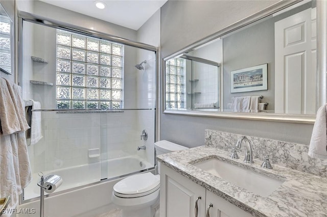 bathroom featuring shower / bath combination with glass door, toilet, and vanity