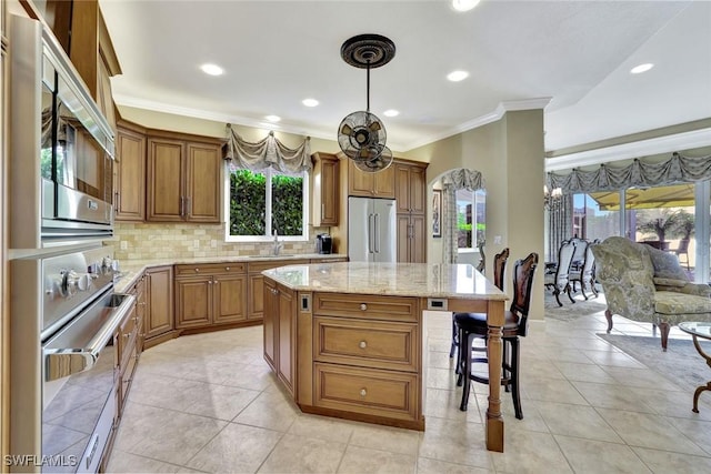 kitchen with brown cabinetry, appliances with stainless steel finishes, a breakfast bar, and a sink