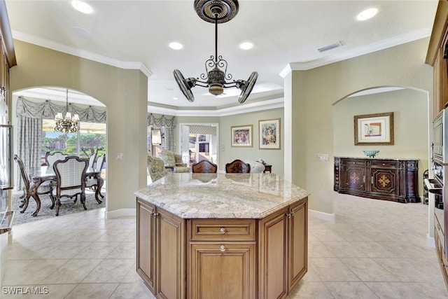 kitchen with crown molding, brown cabinetry, a notable chandelier, and light stone countertops