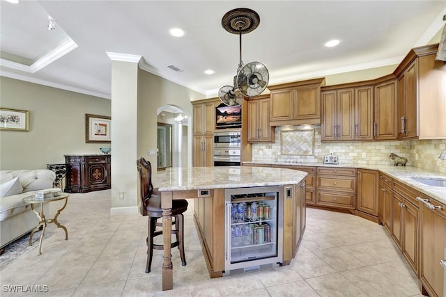 kitchen featuring wine cooler, a kitchen breakfast bar, appliances with stainless steel finishes, arched walkways, and a sink