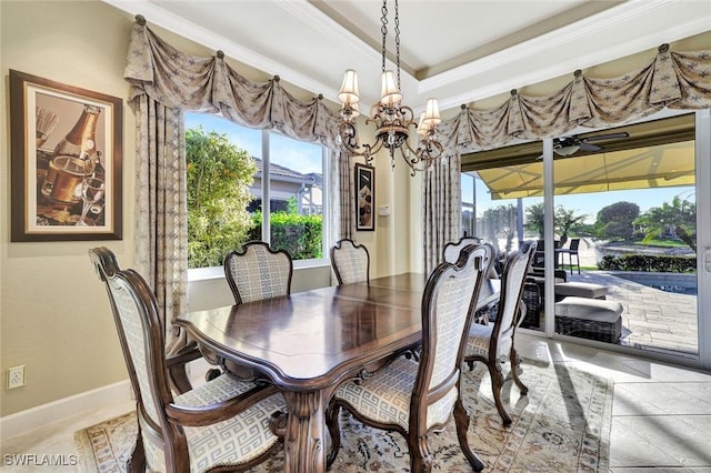 dining area featuring a tray ceiling, baseboards, an inviting chandelier, and crown molding