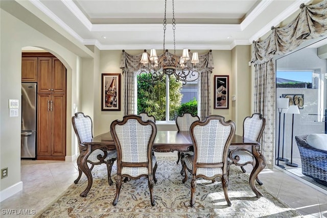 dining space with arched walkways, light tile patterned floors, a raised ceiling, and ornamental molding