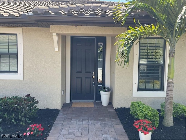 property entrance featuring stucco siding and a tiled roof