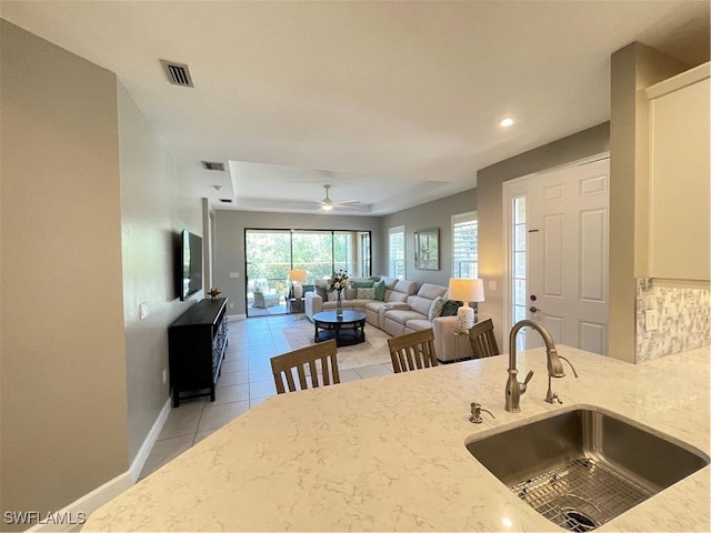 kitchen with a sink, visible vents, light stone countertops, and baseboards