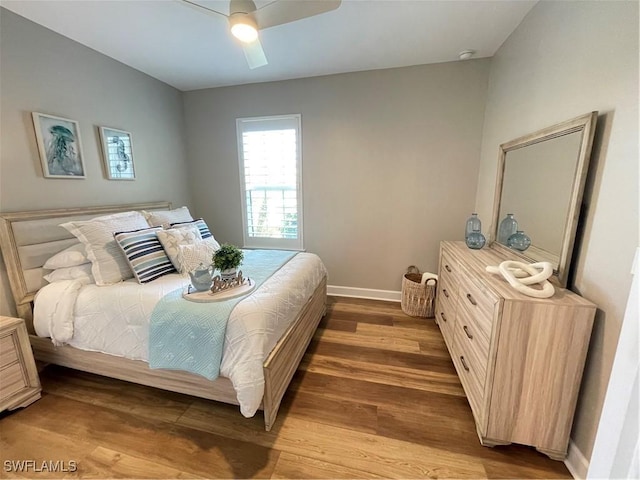 bedroom featuring baseboards, wood finished floors, and a ceiling fan