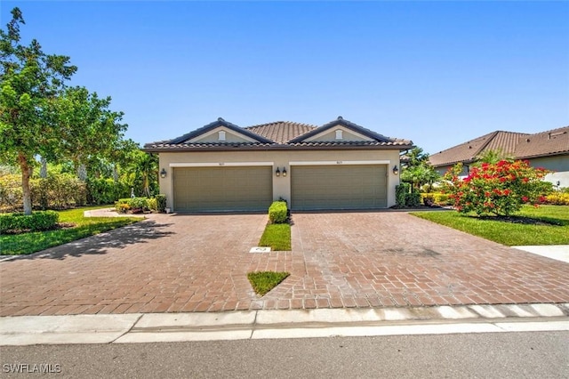 view of front of property featuring a tile roof, an attached garage, driveway, and stucco siding