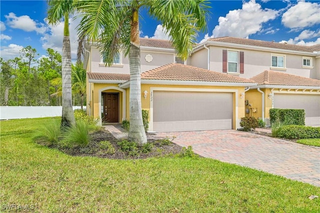 mediterranean / spanish-style home with a garage, a front lawn, decorative driveway, and stucco siding