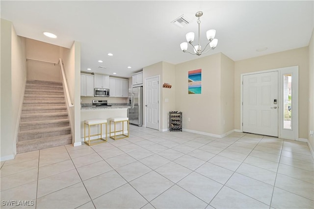 interior space with baseboards, white cabinets, decorative light fixtures, stainless steel appliances, and light countertops