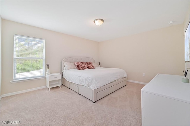 bedroom with light colored carpet and baseboards