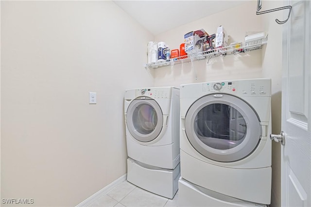 washroom featuring laundry area, light tile patterned flooring, washing machine and clothes dryer, and baseboards