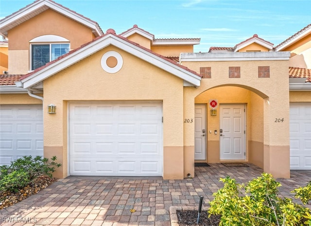 view of property with a tiled roof, decorative driveway, and stucco siding