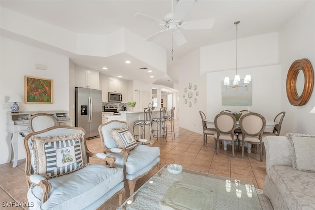 living area featuring light tile patterned flooring, recessed lighting, ceiling fan with notable chandelier, and a high ceiling