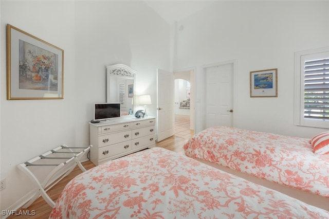 bedroom with light wood-style flooring and high vaulted ceiling