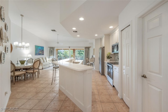 kitchen featuring light tile patterned floors, appliances with stainless steel finishes, a breakfast bar, and light countertops