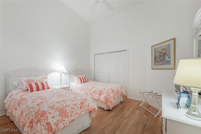 bedroom with high vaulted ceiling, light wood-style flooring, a ceiling fan, a closet, and baseboards