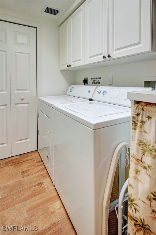 laundry room with light wood-style flooring, visible vents, cabinet space, and washer and clothes dryer