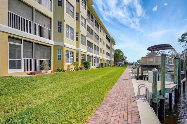 view of property's community featuring a water view, a lawn, and a boat dock