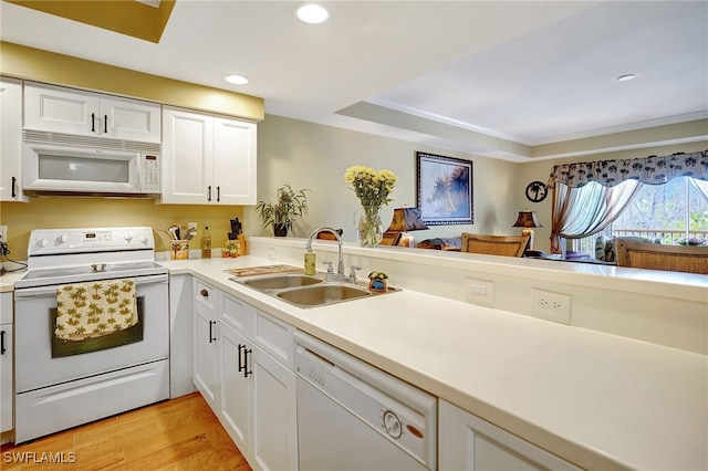 kitchen with light countertops, light wood-style flooring, white cabinets, a sink, and white appliances