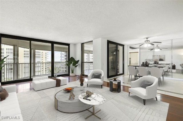 living room with wood finished floors, a textured ceiling, a ceiling fan, and expansive windows