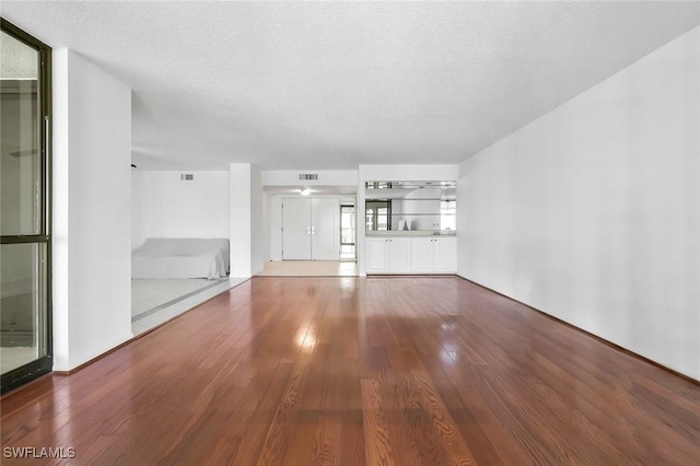 unfurnished living room featuring wood finished floors, visible vents, and a textured ceiling