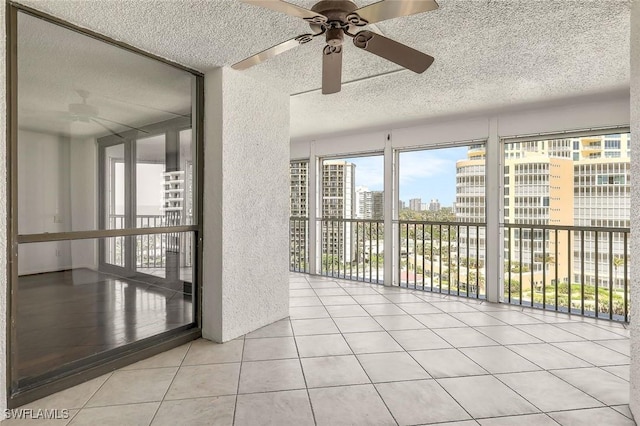 tiled empty room featuring a textured ceiling, a view of city, and ceiling fan