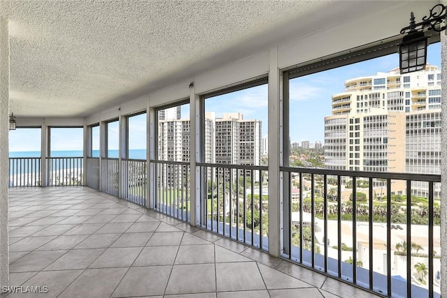 unfurnished sunroom featuring a water view and a view of city