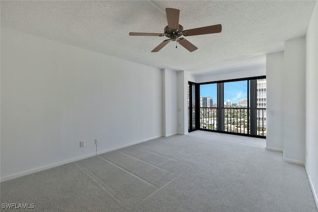 empty room featuring baseboards, a ceiling fan, carpet flooring, and a textured ceiling