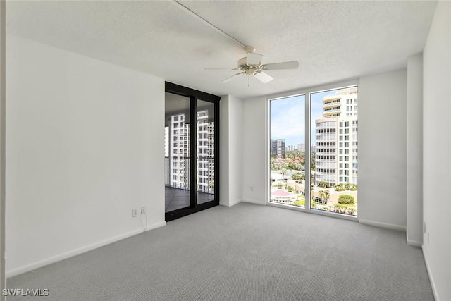 spare room with expansive windows, baseboards, a city view, and carpet flooring