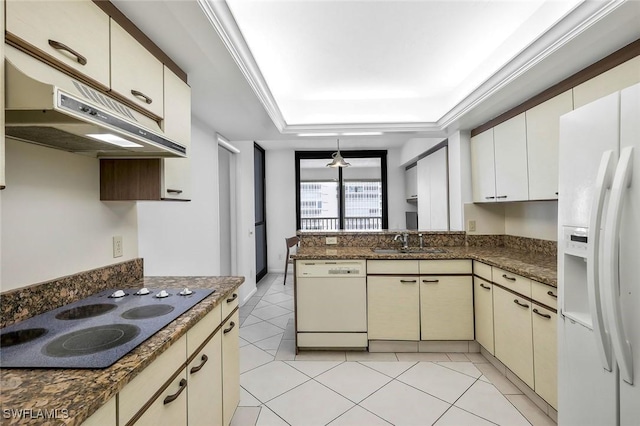 kitchen featuring white appliances, light tile patterned floors, a peninsula, a tray ceiling, and a sink