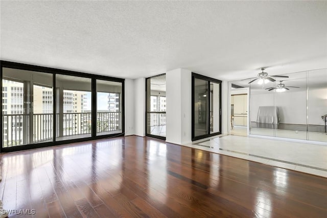 spare room with ceiling fan, a textured ceiling, wood finished floors, and floor to ceiling windows