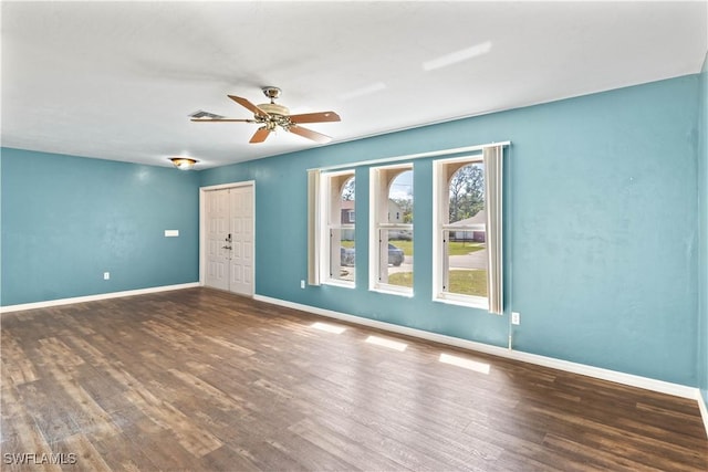 empty room featuring ceiling fan, wood finished floors, and baseboards