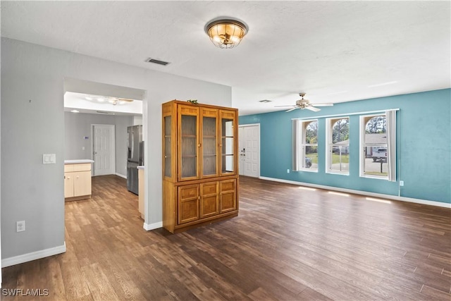 unfurnished living room with ceiling fan, wood finished floors, visible vents, and baseboards