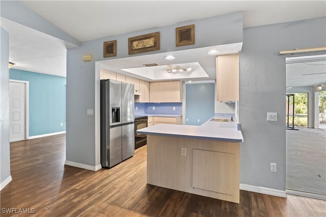 kitchen with stainless steel fridge, a peninsula, baseboards, and wood finished floors