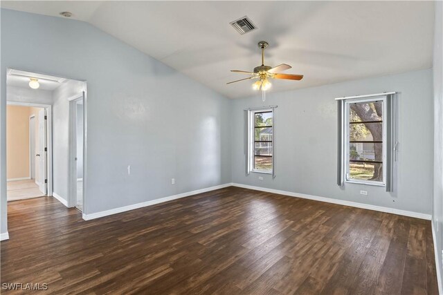 spare room featuring dark wood-style floors, visible vents, vaulted ceiling, ceiling fan, and baseboards