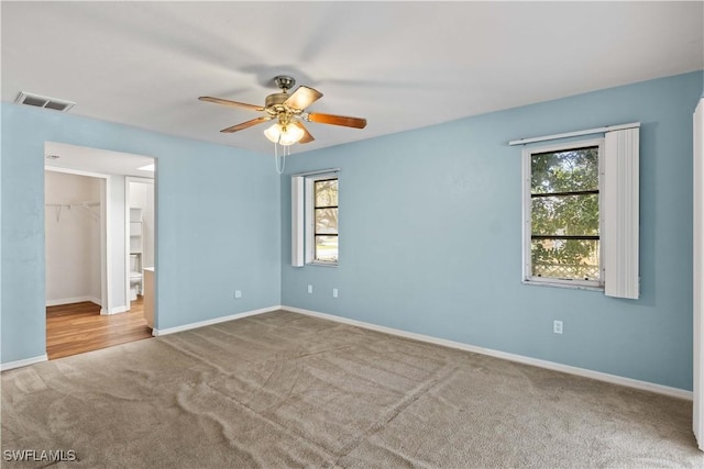 empty room with carpet floors, a healthy amount of sunlight, visible vents, and baseboards